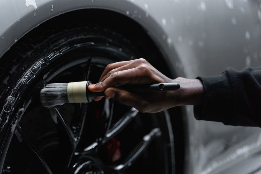 Detailing brush working suds through a dark alloy wheel
